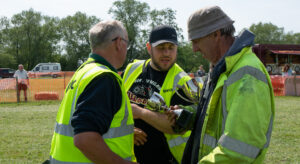 Club members in high visibility clothing holding winners' cups, deep in conversation.