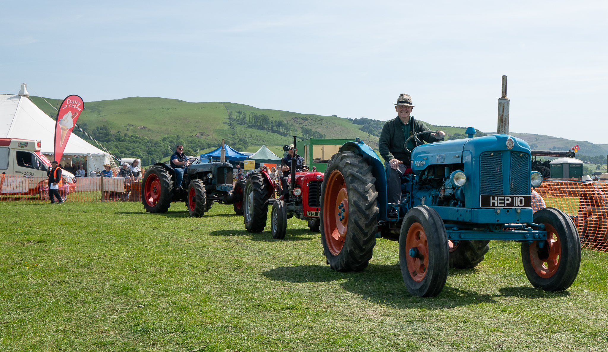 People driving tractors in the sunshine in a field