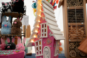 A bright pink model house with pointy white roof, lights and fairy tail patterns around the outside.